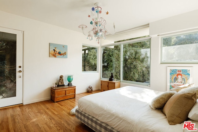 bedroom featuring an inviting chandelier and light hardwood / wood-style floors