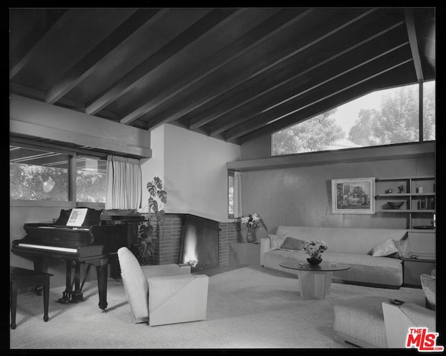 carpeted living room featuring a brick fireplace and vaulted ceiling with beams