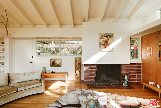 living room featuring beamed ceiling, a fireplace, and hardwood / wood-style floors