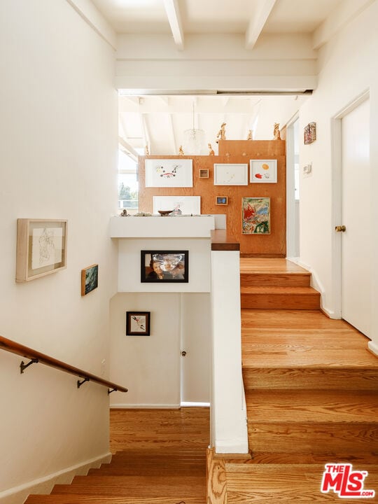 stairs featuring wood-type flooring and beam ceiling