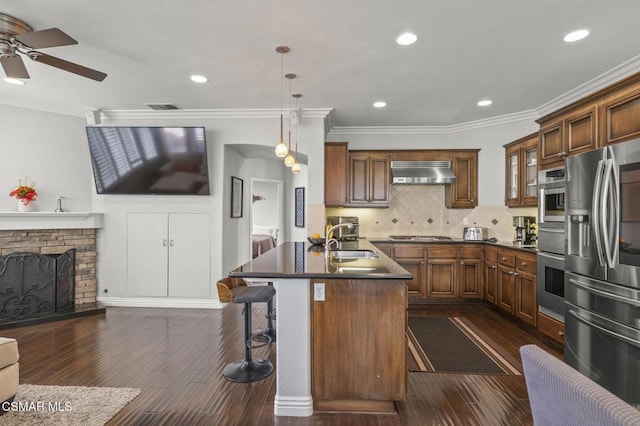 kitchen featuring a breakfast bar area, hanging light fixtures, kitchen peninsula, stainless steel appliances, and wall chimney range hood