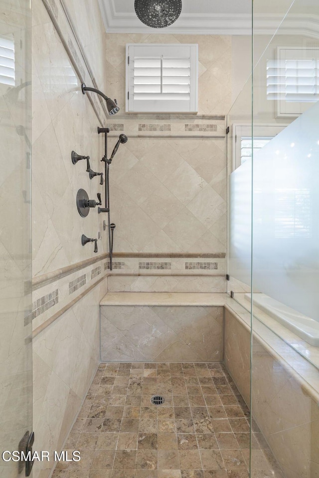 bathroom with ornamental molding and a tile shower