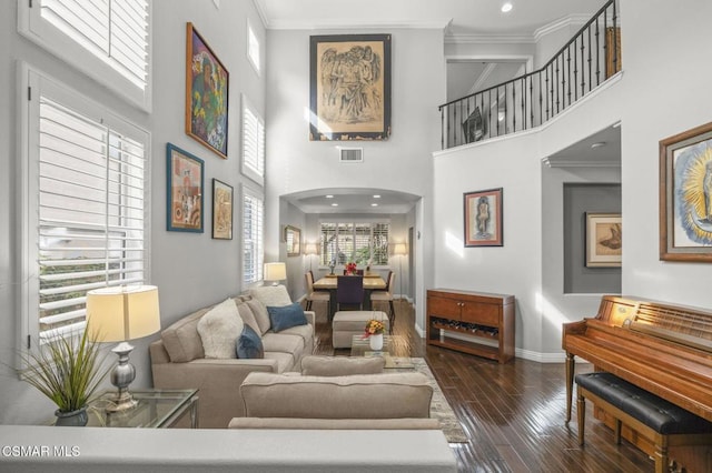 living room featuring crown molding, dark hardwood / wood-style floors, and a towering ceiling