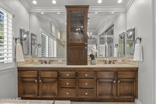 bathroom featuring ornamental molding, a healthy amount of sunlight, backsplash, and vanity