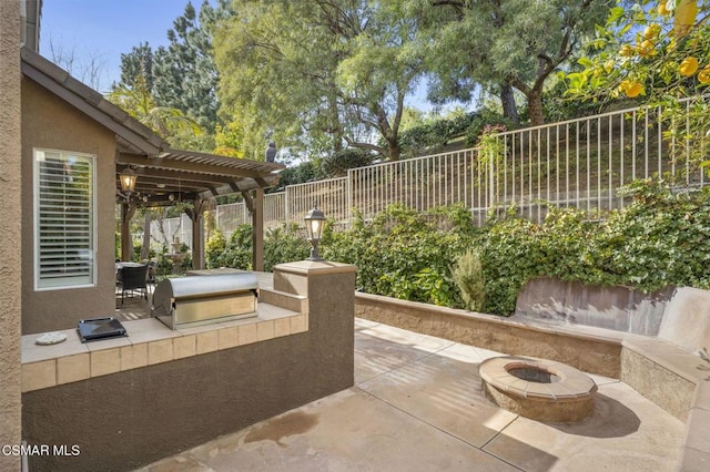 view of patio featuring grilling area, a pergola, exterior kitchen, and a fire pit