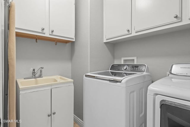 washroom featuring sink, washer and clothes dryer, and cabinets