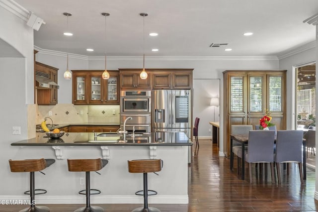 kitchen featuring sink, extractor fan, kitchen peninsula, pendant lighting, and stainless steel appliances