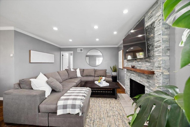 living room with hardwood / wood-style flooring, crown molding, and a stone fireplace