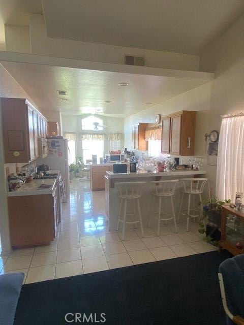 kitchen with backsplash, a kitchen bar, and light tile patterned floors