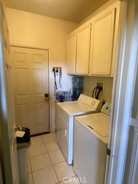 laundry room with light tile patterned floors, washing machine and dryer, and cabinets