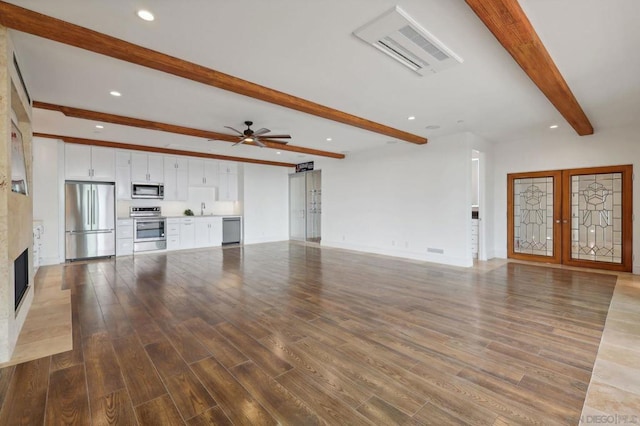 unfurnished living room with french doors, wood-type flooring, a large fireplace, ceiling fan, and beam ceiling