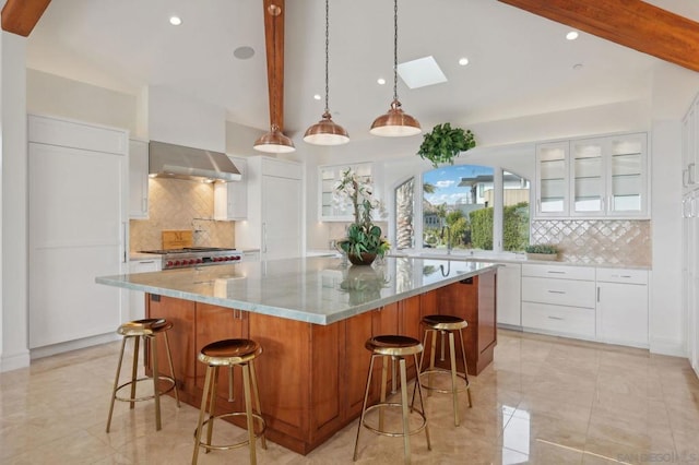 kitchen with a spacious island, wall chimney exhaust hood, a breakfast bar area, white cabinetry, and pendant lighting