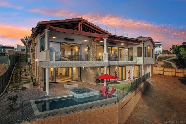 back house at dusk featuring a jacuzzi and a patio