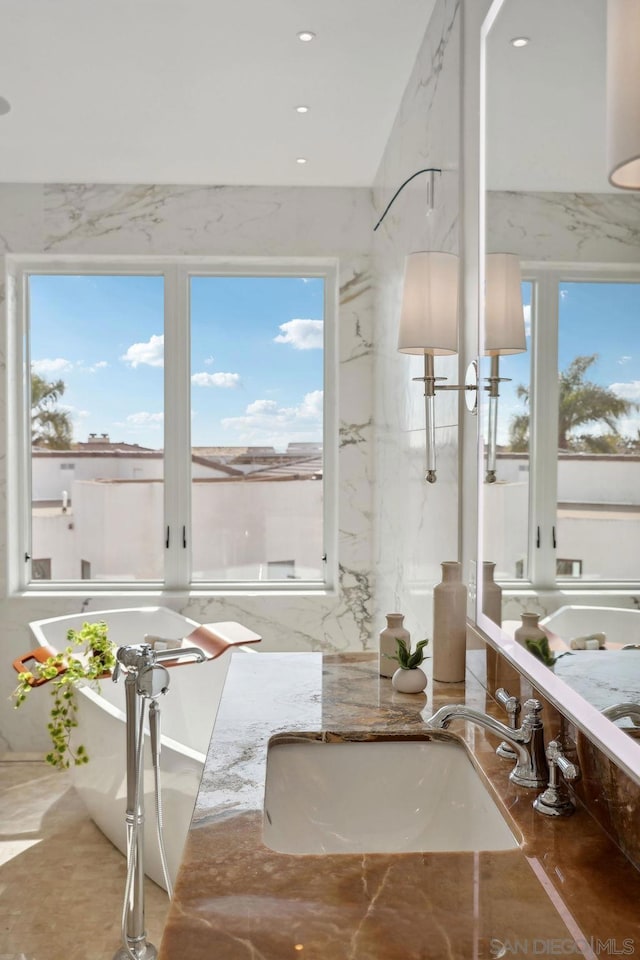 bathroom featuring plenty of natural light, sink, and a washtub