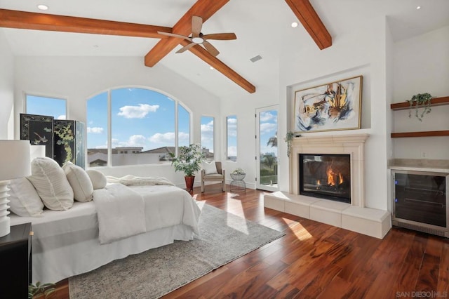 bedroom featuring access to exterior, a tiled fireplace, hardwood / wood-style floors, and beam ceiling