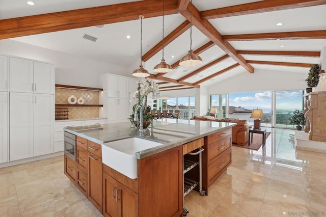 kitchen featuring sink, pendant lighting, light stone countertops, a kitchen island with sink, and white cabinets