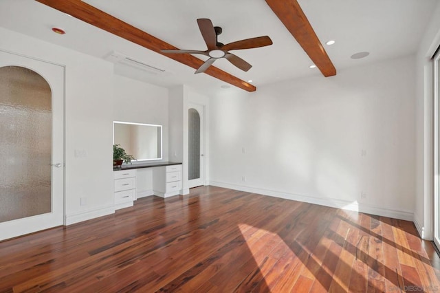 unfurnished living room featuring ceiling fan, hardwood / wood-style flooring, built in desk, and beamed ceiling