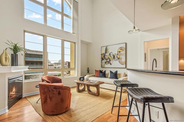 living room with a towering ceiling and light wood-type flooring