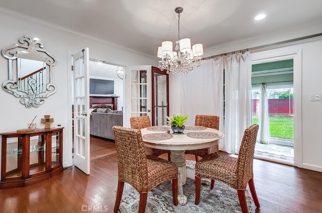 dining area with an inviting chandelier, ornamental molding, dark hardwood / wood-style floors, and french doors