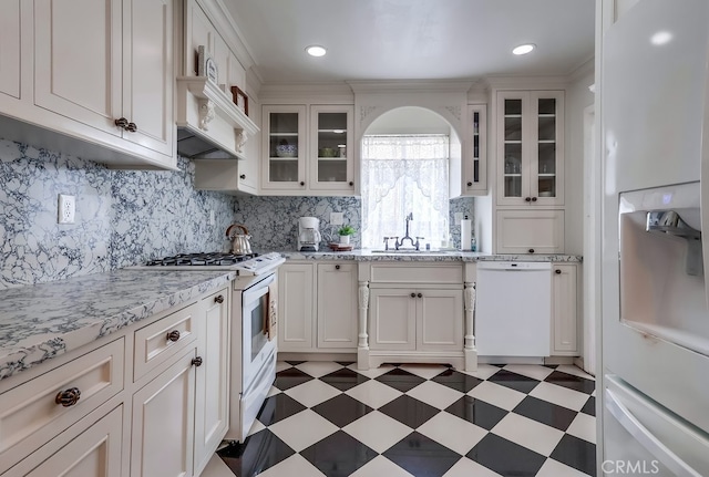 kitchen featuring sink, white appliances, white cabinets, and backsplash