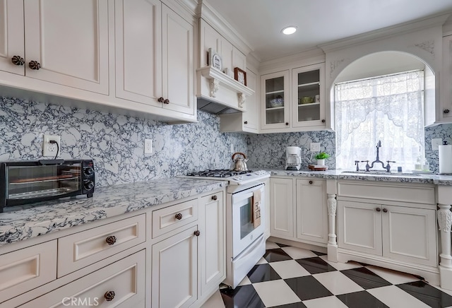 kitchen with sink, white cabinets, decorative backsplash, white range with gas stovetop, and light stone countertops