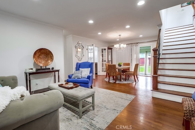 living room with wood-type flooring, a notable chandelier, and crown molding