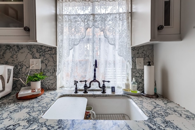 details with tasteful backsplash, light stone countertops, and sink