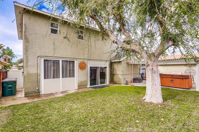 back of house featuring a yard and a hot tub