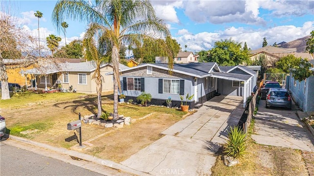 view of front of property with a residential view, concrete driveway, and a front yard