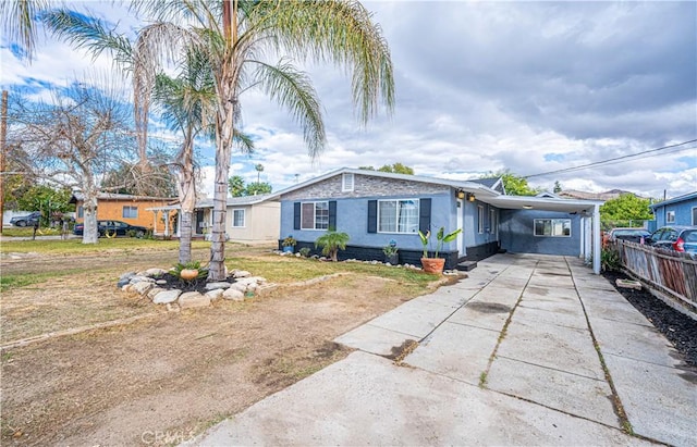 view of front of house featuring driveway, a carport, and fence