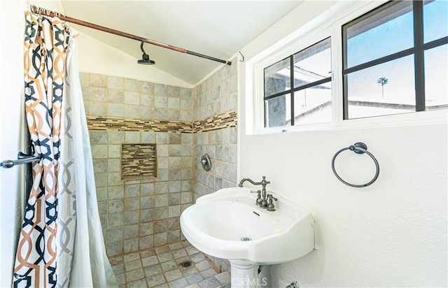 full bath with lofted ceiling, a sink, and a tile shower