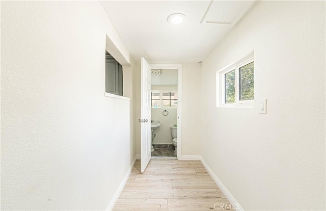 hall with light wood-style floors and baseboards