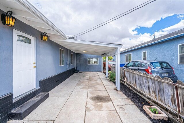 view of patio featuring fence, a carport, and concrete driveway