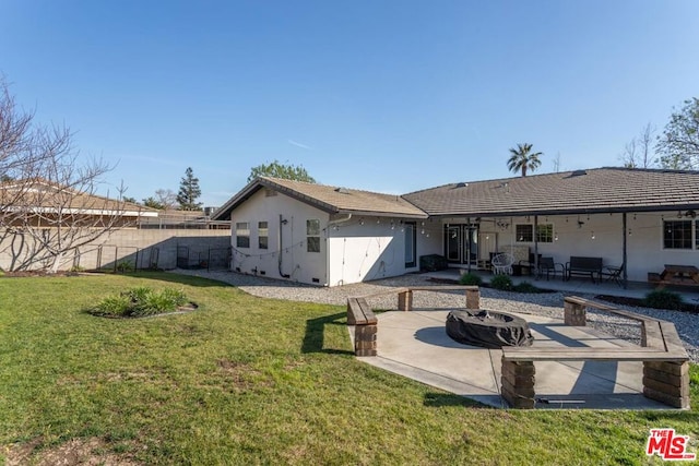 back of house with a lawn, a patio area, and an outdoor fire pit