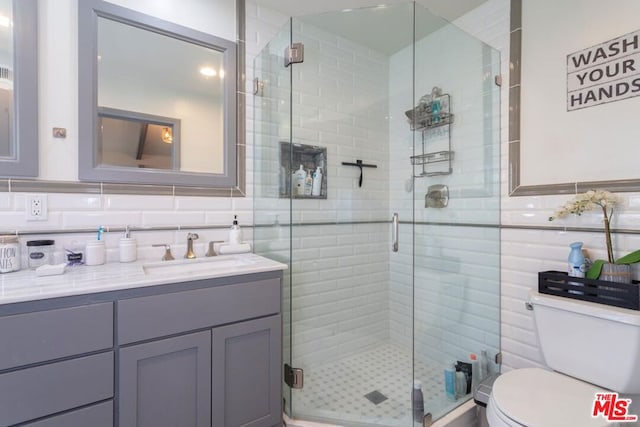 bathroom with vanity, toilet, and a shower with door