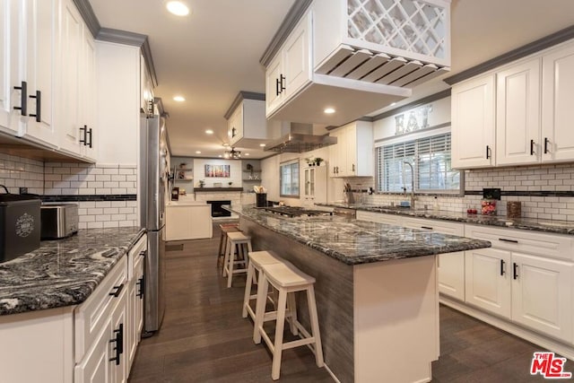 kitchen featuring white cabinetry, dark stone counters, a kitchen breakfast bar, and a kitchen island