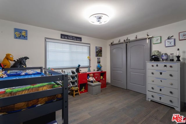 bedroom with dark wood-type flooring, a barn door, and a closet