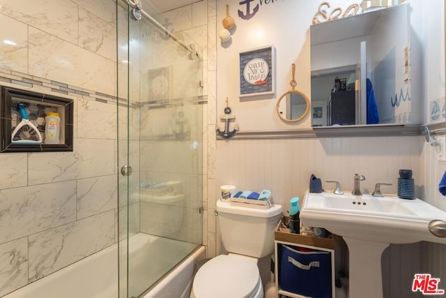 full bathroom with sink, combined bath / shower with glass door, and toilet