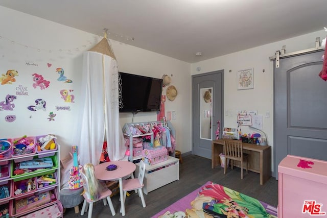 playroom with a barn door and dark wood-type flooring