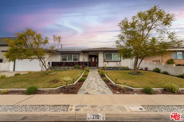 ranch-style home featuring a garage and a yard