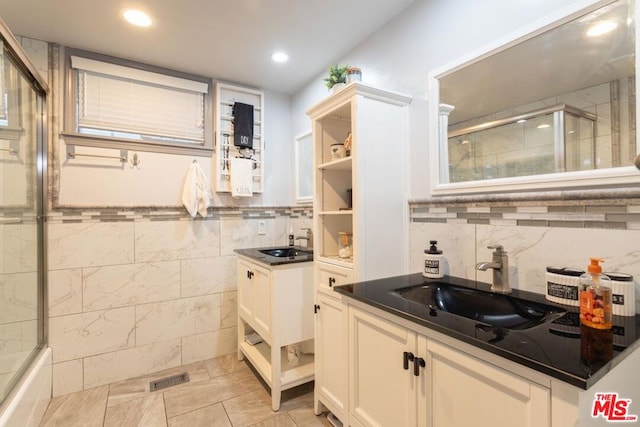 kitchen with white cabinetry, sink, and tile walls