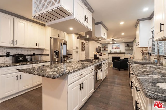 kitchen featuring dark wood-type flooring, appliances with stainless steel finishes, dark stone countertops, white cabinets, and a kitchen island