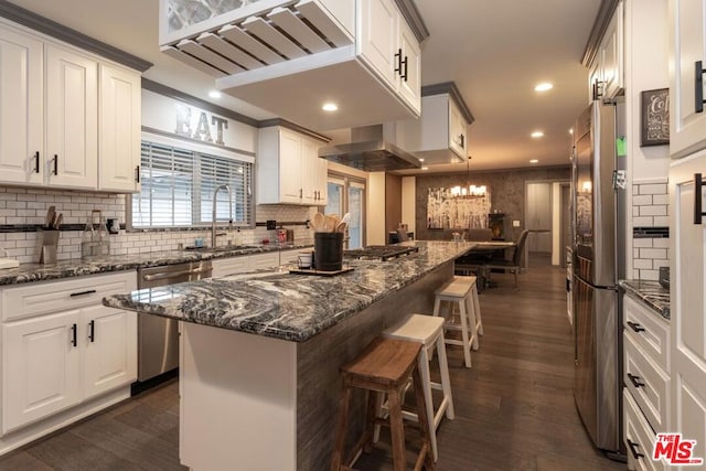 kitchen with dark stone counters, a center island, white cabinets, and appliances with stainless steel finishes