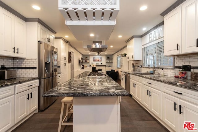 kitchen featuring sink, white cabinetry, dark stone counters, a kitchen island, and stainless steel appliances