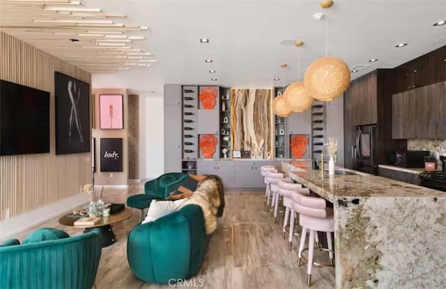 kitchen featuring sink, decorative light fixtures, a center island, dark brown cabinets, and refrigerator with ice dispenser