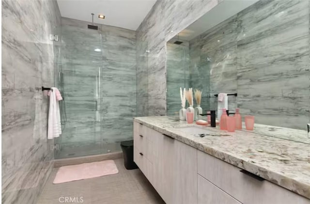 bathroom featuring vanity, toilet, tile walls, and a shower with shower door