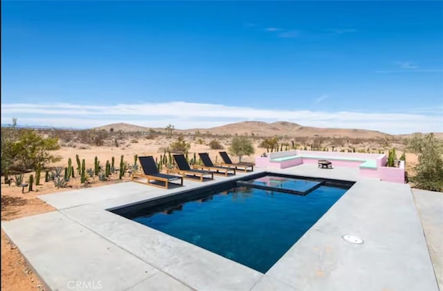 view of pool featuring a patio, a mountain view, and an in ground hot tub