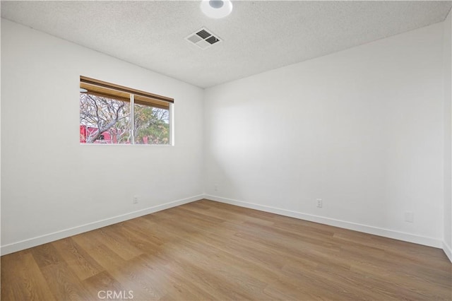 unfurnished room featuring hardwood / wood-style flooring and a textured ceiling