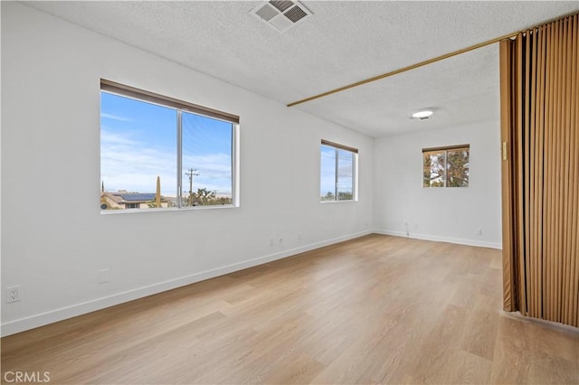 unfurnished room with light hardwood / wood-style floors and a textured ceiling