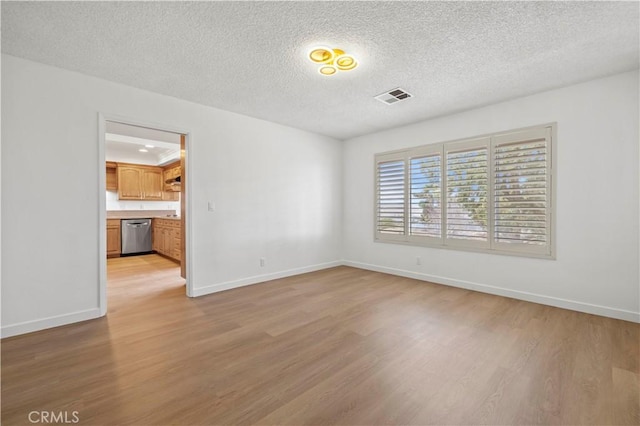 empty room with a textured ceiling and light hardwood / wood-style floors